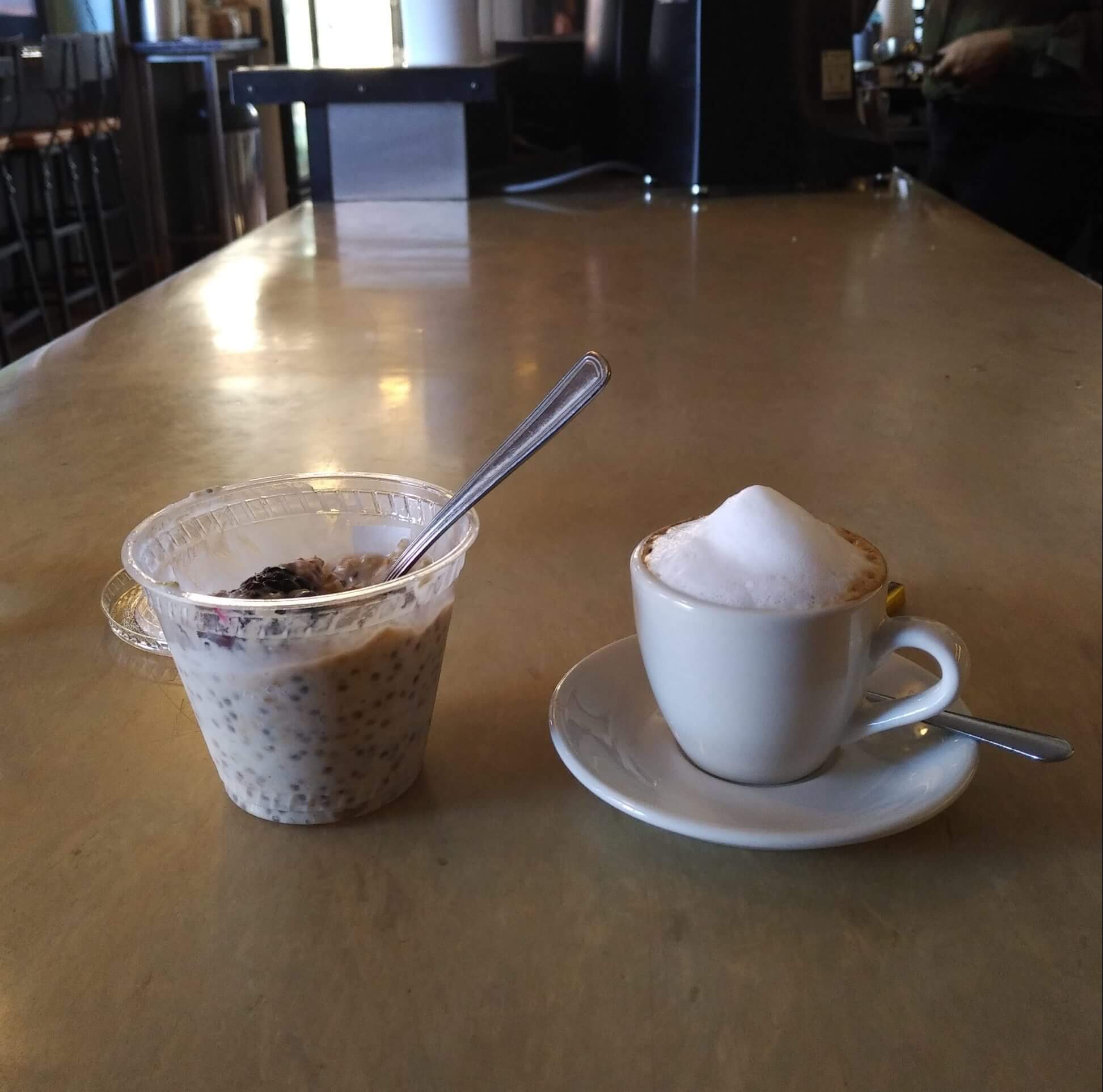 macchiato beside a small cup of oatmeal with berries
