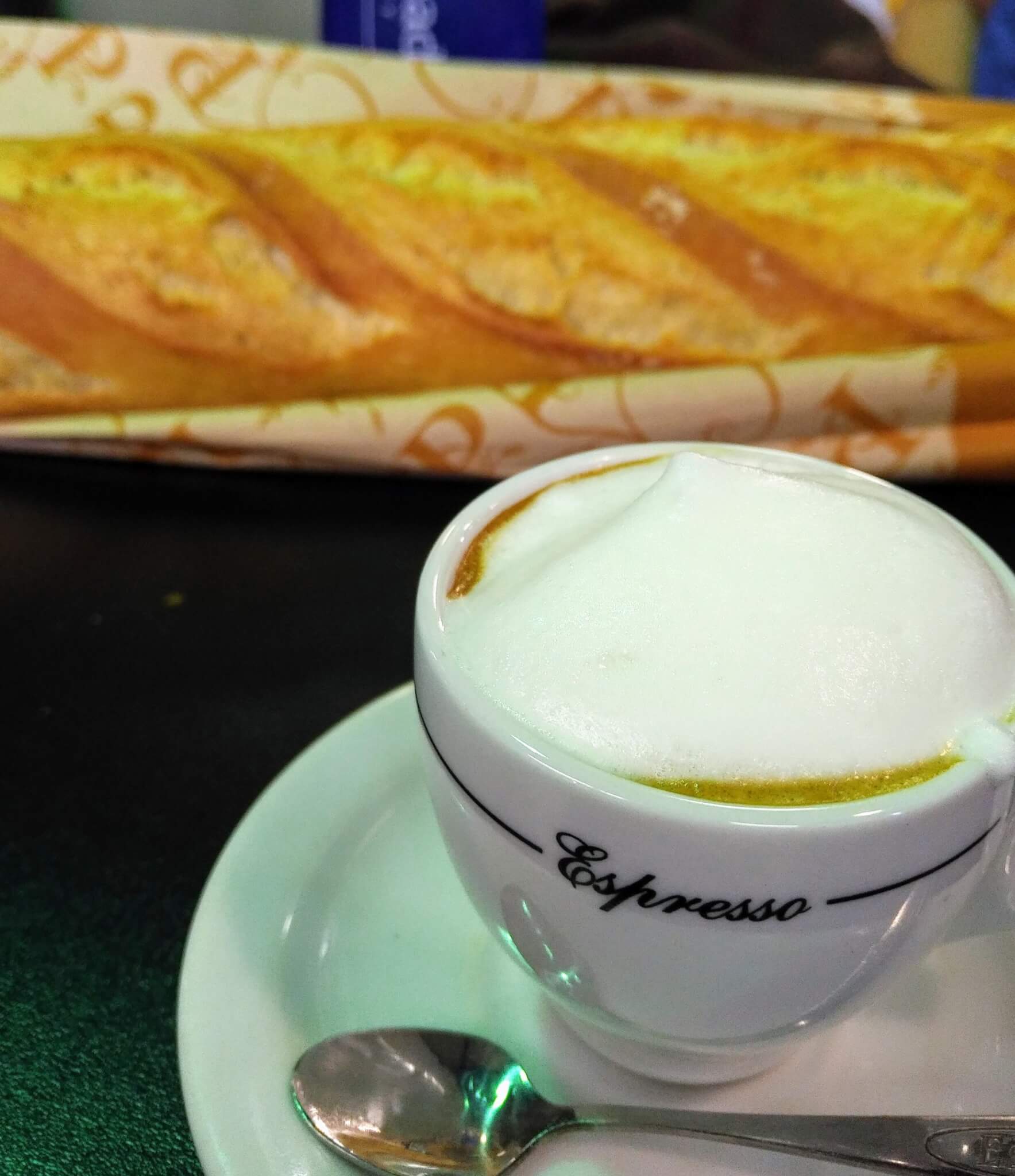 macchiato with a baguette sitting on the table behind