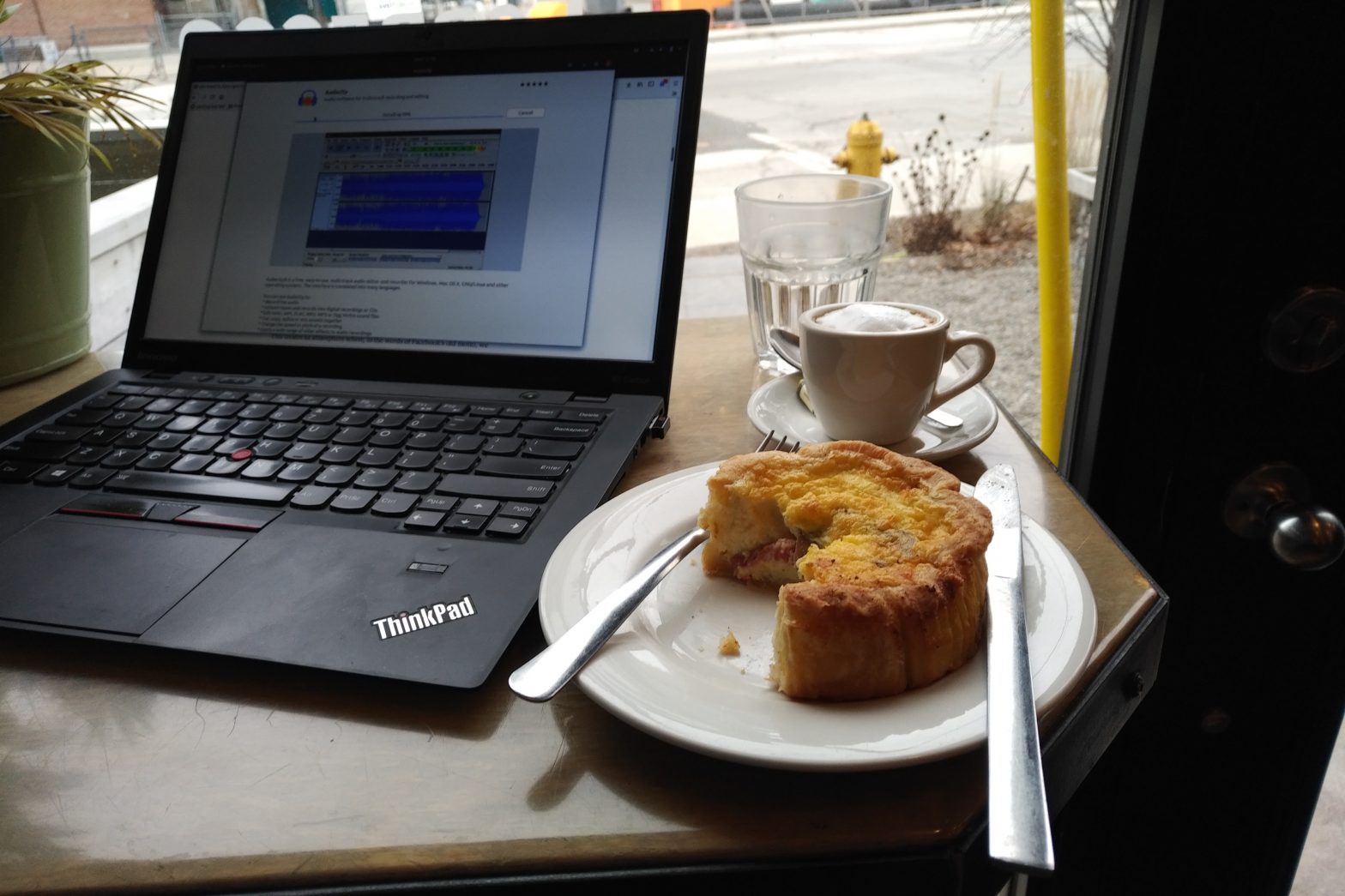 laptop, quiche and coffee in window looking out on street
