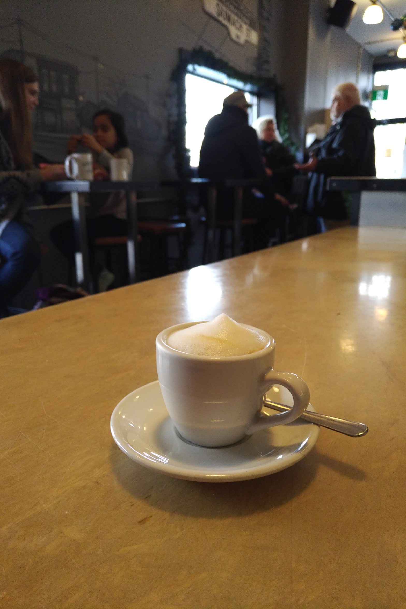 a small coffee, with patrons in various groups, blurred in the background